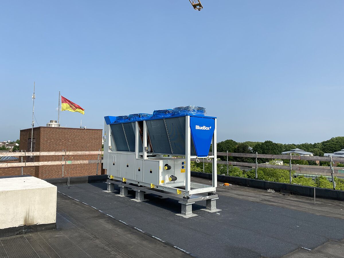 Das Bild zeigt die Wärmepumpe, wie sie auf dem Dach des neuen Rathauses steht.