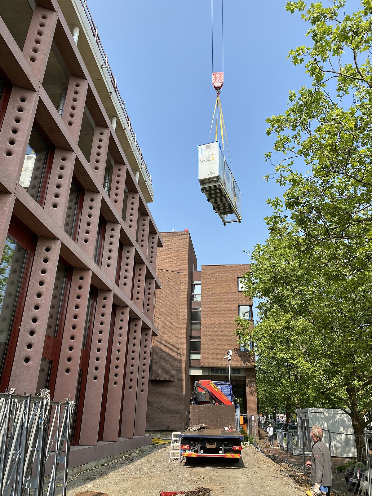 Eine Wärmepumpe schwebt per Kran auf das Dach des neuen Rathauses Langenhagen.